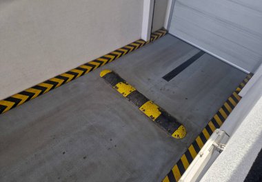 Otomatik bariyerler ve güvenlik işaretleriyle donatılmış bir yeraltı garajına ya da otoparkın çıkışına. Sarı-siyah kuluçka ve yön okları da dahil olmak üzere yatay trafik işaretleri, verilen çarpışma alanının güvenli yönelimi için hizmet verir