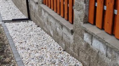 Bir kamyonun veya römorkun el arabasıyla bahçedeki çiçek yataklarına saman taşı gibi gri nehir taşlarının teslimatı. Örülmemiş siyah kumaşın üstünü kürekle ve tırmıkla..