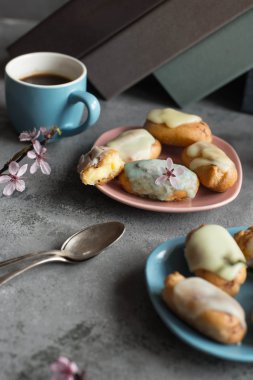 Profiterol tereyağı krema ve plaka gri arka plan üzerinde tepesi ile. Kahve molası Duraklat. Pastel tonları.