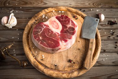Ham taze sarımsak, biber ve baharat kasap cleaver ile ahşap kesme tahtası üzerinde ile kesilmiş Dana çapraz. 