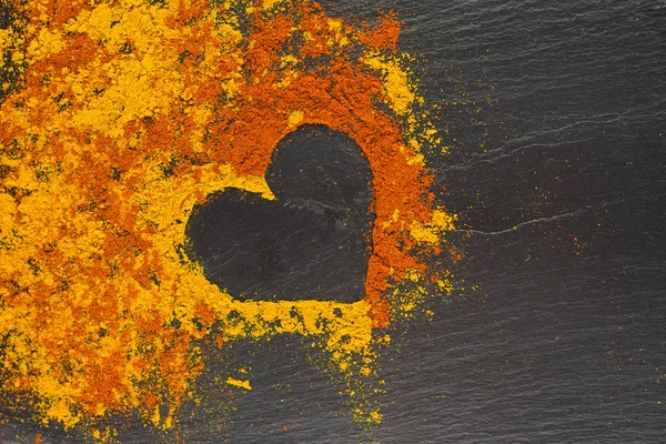 Corazón de San Valentín de especias curry y pimentón sobre el fondo negro. 14 de febrero . — Foto de Stock