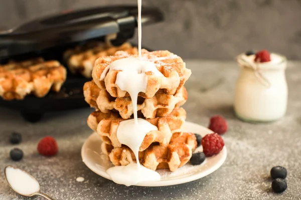 Waffles belgas caseiros com frutos silvestres, mirtilos, framboesas e iogurte derramado sobre fundo cinzento . — Fotografia de Stock