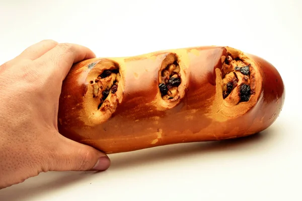 Hand holding long loaf, Russian rye bread, crusty black raisin walnut nut sandwich closeup