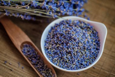 Beyaz bir porselen kasede kurutulmuş lavanta çiçekleri.