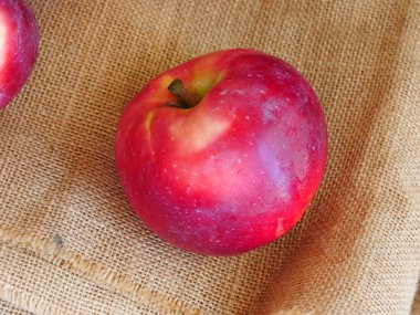 Taze kırmızı elmalar, çuval bezi arka planı, lezzetli ve sulu.