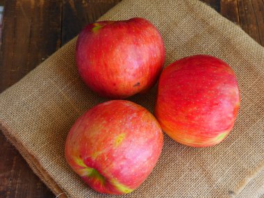 Taze kırmızı elmalar, çuval bezi arka planı, lezzetli ve sulu.