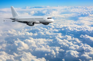 Commercial passenger plane flying above clouds clipart