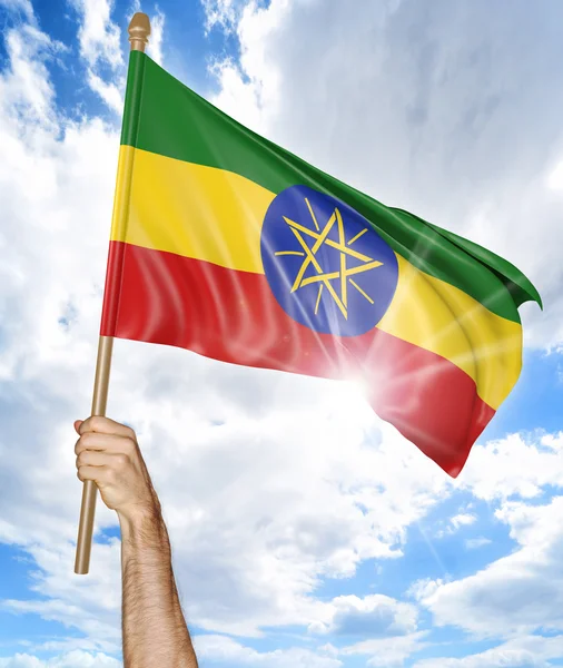 Mano de la persona sosteniendo la bandera nacional etíope y agitándola en el cielo, representación 3D —  Fotos de Stock