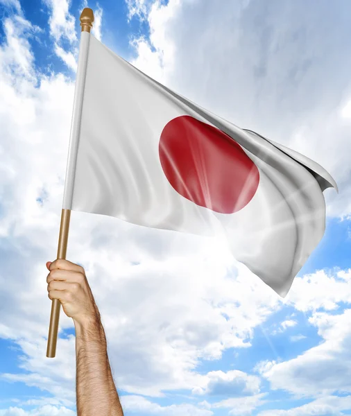 Person 's hand holding the Japanese national flag and waving it in the sky, 3D rendering — стоковое фото