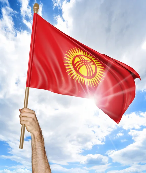 Person's hand holding the Kyrgyzstan national flag and waving it in the sky, 3D rendering — Stock Photo, Image