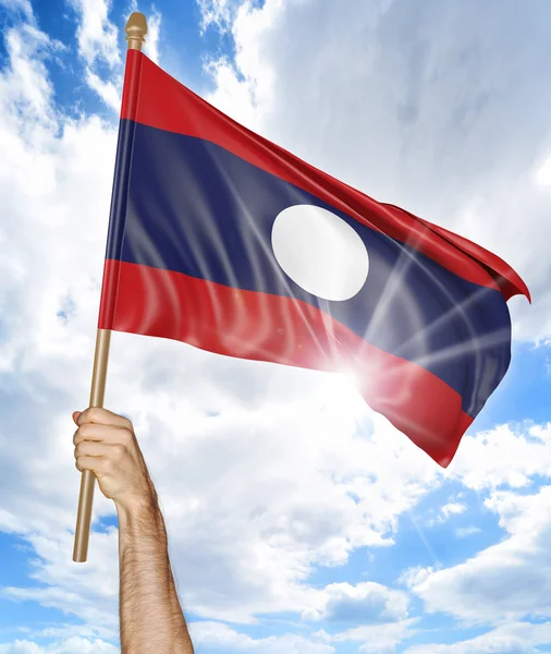 Mano de la persona sosteniendo la bandera nacional de Laos y agitándola en el cielo, representación 3D —  Fotos de Stock