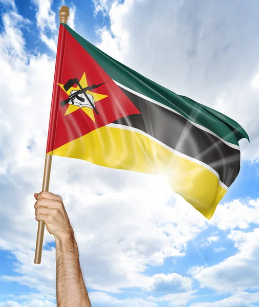 Mano de la persona sosteniendo la bandera nacional mozambiqueña y agitándola en el cielo, representación 3D —  Fotos de Stock