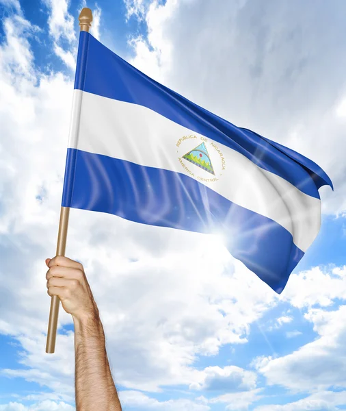 Mano de persona sosteniendo la bandera nacional de Nicaragua y ondeándola en el cielo, representación 3D —  Fotos de Stock