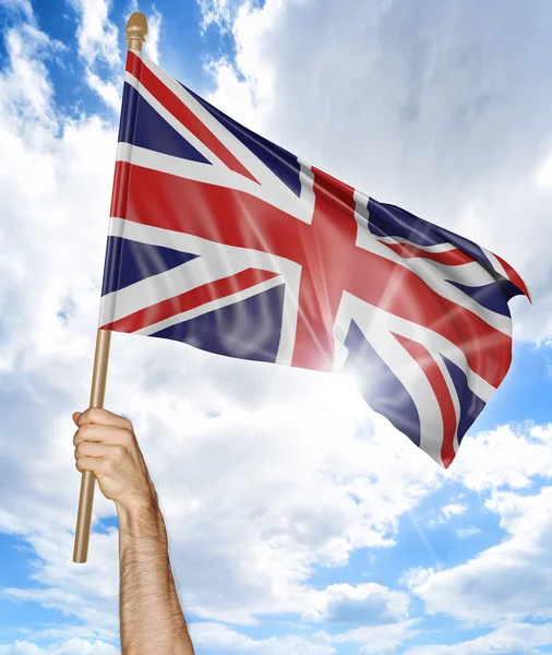 Person's hand holding the British national flag and waving it in the sky, 3D rendering — Stock Photo, Image