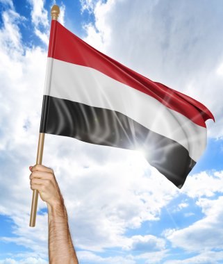 Person's hand holding the Yemen national flag and waving it in the sky, 3D rendering clipart