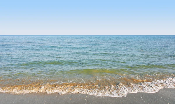 ชายหาดที่เงียบสงบที่มีคลื่นอ่อนโยนทิ้งชายฝั่ง — ภาพถ่ายสต็อก