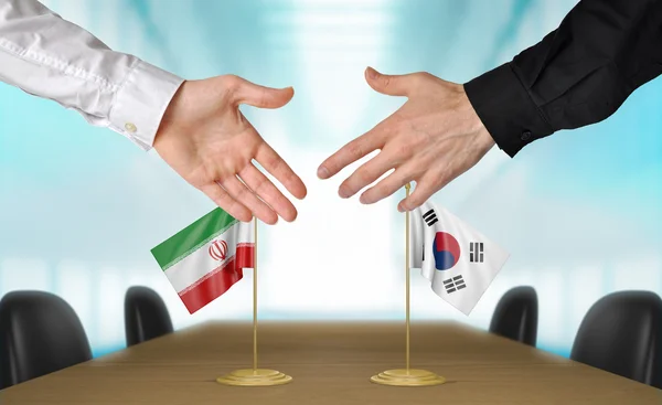 Iran and South Korea diplomats shaking hands to agree deal