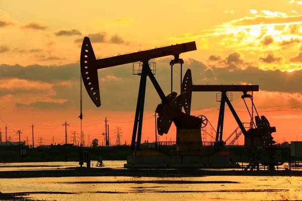 Oil field site, in the evening, oil pumps are running