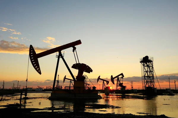 Oil field site, in the evening, oil pumps are running