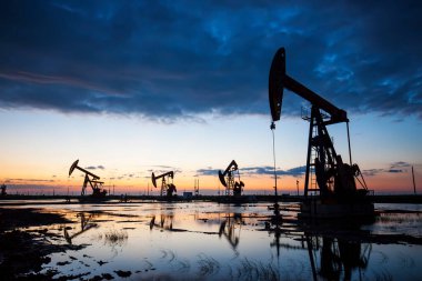 Oil field site, in the evening, oil pumps are running clipart