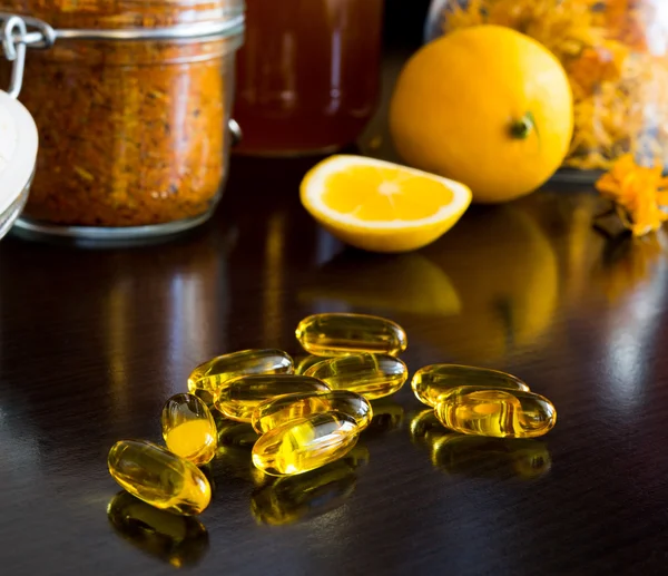 Capsule vitaminiche gialle, su sfondo limone, miele e spezie — Foto Stock