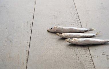 Ahşap masa üzerinde üç sardalya