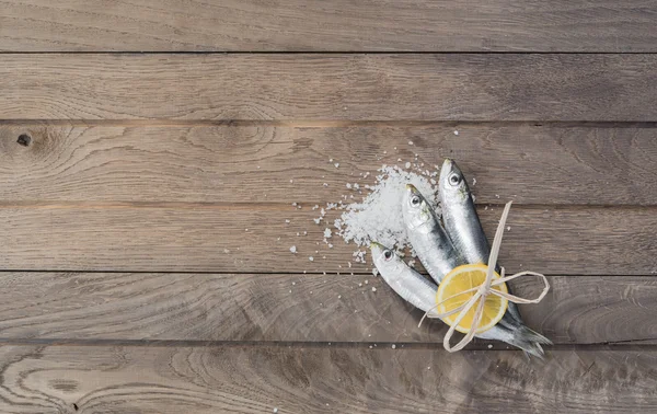 Trois sardines enveloppées de citron sur une table en bois — Photo