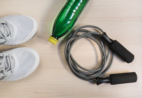 Ahşap zemin üzerinde spor ayakkabı ve şişe suyu ile ip atlama