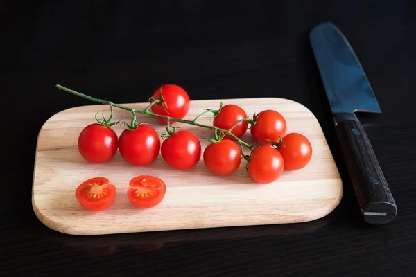 Tomates cereja vermelhos na tábua de corte — Fotografia de Stock