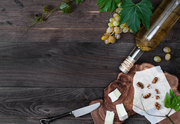 Bottle of wine, fresh grape, cheese and walnut on wooden background — Stock Photo, Image