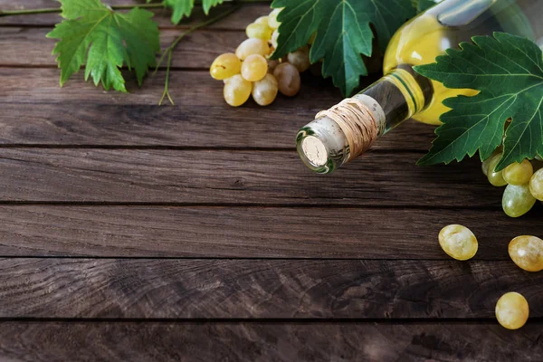 -Bir şişe şarap ve ahşap zemin üzerine taze üzüm