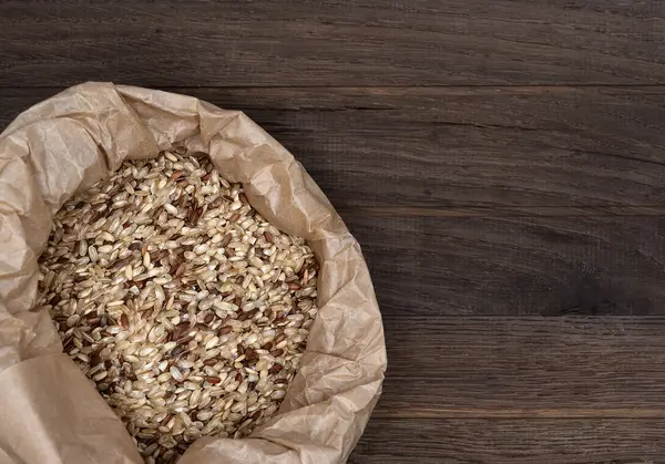 Bag with brown rice on wooden backgroung — Stock Photo, Image