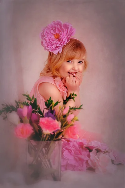 Blonde girl in a pink dress with a flower in her hair — Stock Photo, Image