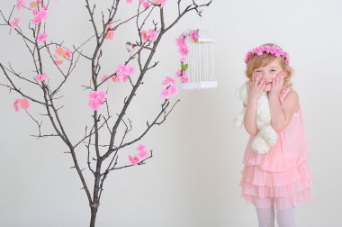kız pembe bir çelenk ve pembe bir elbise ile bir flowerin üzerinde bir kuş