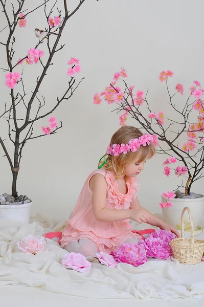 The girl in a pink dress and a wreath on his head