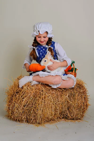 Girl in the hay feeding the Easter Bunny carrots. — Stock Photo, Image