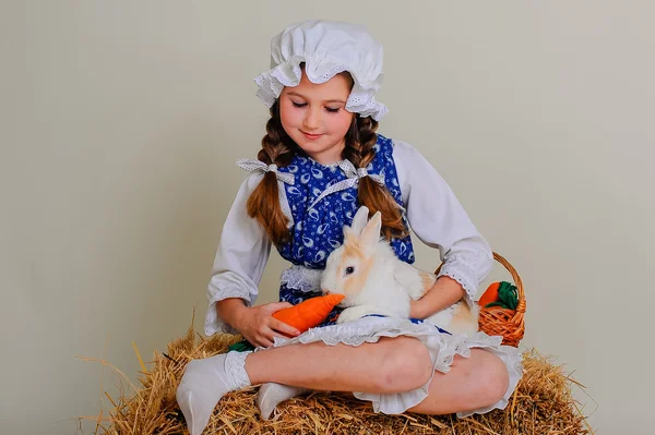 Girl in the hay feeding the Easter Bunny carrots. — Stock Photo, Image