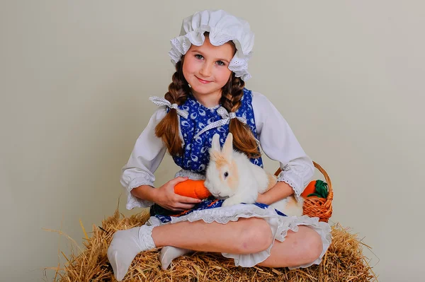 Girl in the hay feeding the Easter Bunny carrots. — Stock Photo, Image