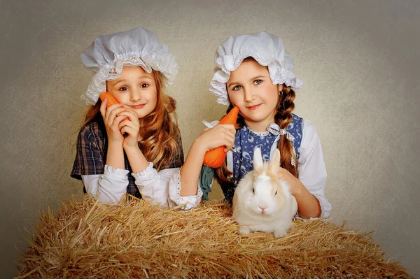 Girl with a rabbit on the hay and a carrot. — Stock Photo, Image