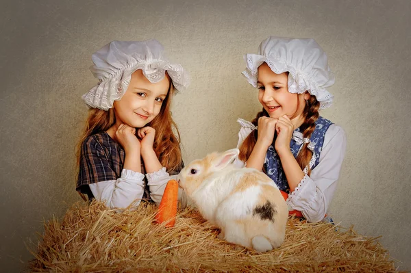 Girl in the hay feeding the Easter Bunny carrots. — Stock Photo, Image