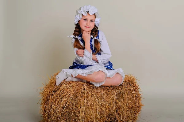 Girl in dress sitting on a rustic vintage straw bale. — Stock Photo, Image