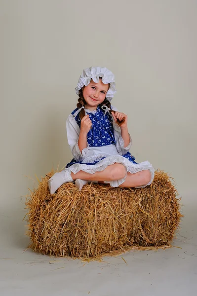 Girl in dress sitting on a rustic vintage straw bale. — Stock Photo, Image