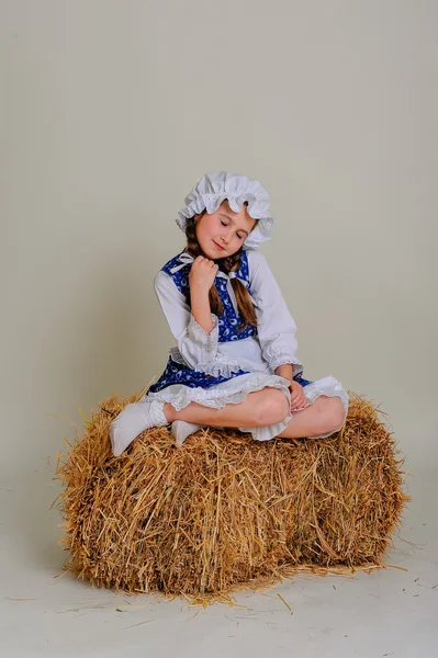 Girl in dress sitting on a rustic vintage straw bale. — Stock Photo, Image