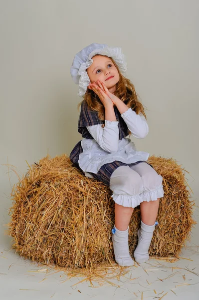 Girl in dress sitting on a rustic vintage straw bale — Stock Photo, Image