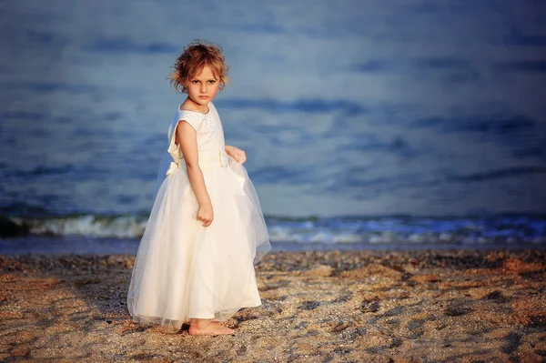 Menina em um vestido branco caminha na praia do mar — Fotografia de Stock