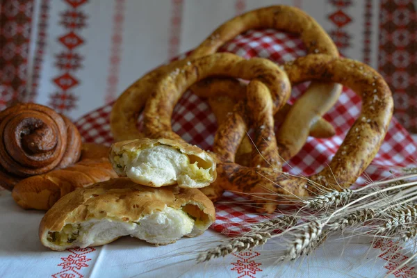 Pan casero: pan de pretzel Caracol con semillas de amapola, un croissant con mermelada y una rebanada de pastel de queso —  Fotos de Stock