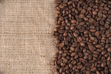 Kavrulmuş kahve çekirdekleri jüt arkaplanda ve mesajın için yer var.