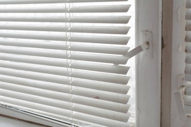 Tahta pencere ve beyaz yatay panjurlar. Eski ahşap bir pencerenin parçası.