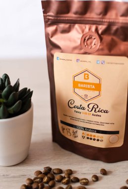 Tiraspol, Moldova - 19 Mart 2021: Deodorant kapaklı yumuşak ambalajlı kahve. Kosta Rika kahvesi,% 100 Arap kahvesi, kahve markası ve beyaz tencerede dekoratif yeşil çiçek. 45 derece açıyla.