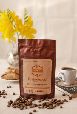 Tiraspol, Moldova - 19 Mart 2021: Deodorant vanalı yumuşak ambalajlı kahve, Arap fasulyesi, eski bir kitap ve şekerlerin üzerinde bir fincan kahve. Yerel marka Barista kahvesi. 45 derece